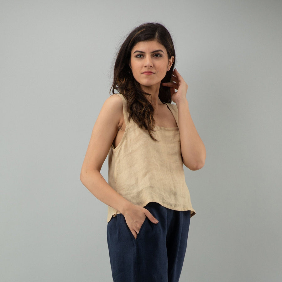 Beige Linen Sleeveless Crop Top: angled pose in Beige crop top, hand raised to hair