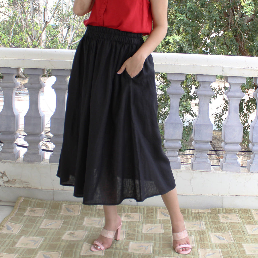 Black Linen Midi Skirt, Pleated Flared: Black midi skirt, hand in pocket on balcony