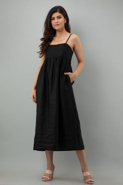 Black Sleeveless Linen Maxi Dress: woman in black sleeveless linen maxi dress with thin straps, hand in pocket, front view