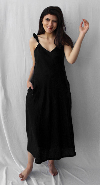 Black Sleeveless Linen Tunic Dress, V-Neck: woman in Black linen tunic dress with one arm raised, three quarter view