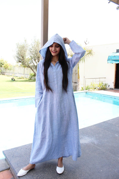 Blue Hooded Linen Maxi Dress: woman in light blue linen maxi dress with hood up, hand near face