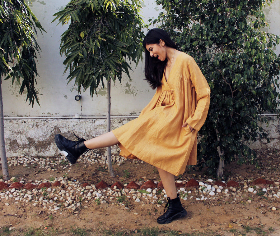 Cottagecore Linen Midi Dress: woman kicking one leg up in mustard linen midi dress and black boots