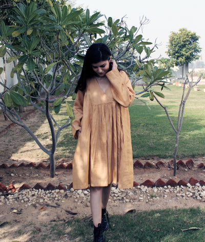 Cottagecore Linen Midi Dress: woman in mustard long sleeve linen midi dress looking down, among trees