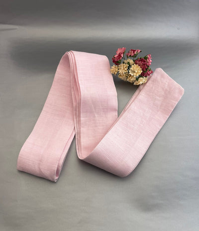 Handmade Linen Belt: pink linen belt folded on grey backdrop with flowers
