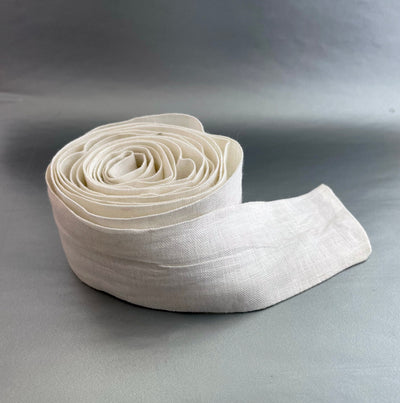 Handmade Maternity Linen Belt: rolled off white linen belt, side view, on a grey background