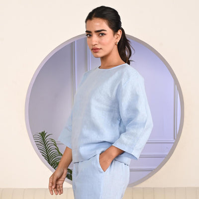 Light Blue Linen Top, 3/4 Sleeve: woman in Sky Blue linen top turning to the side, hand in pocket