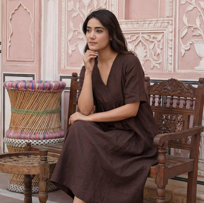 Linen A-Line Dress with Empire Waist: woman seated on a wooden chair in Brown V-neck dress