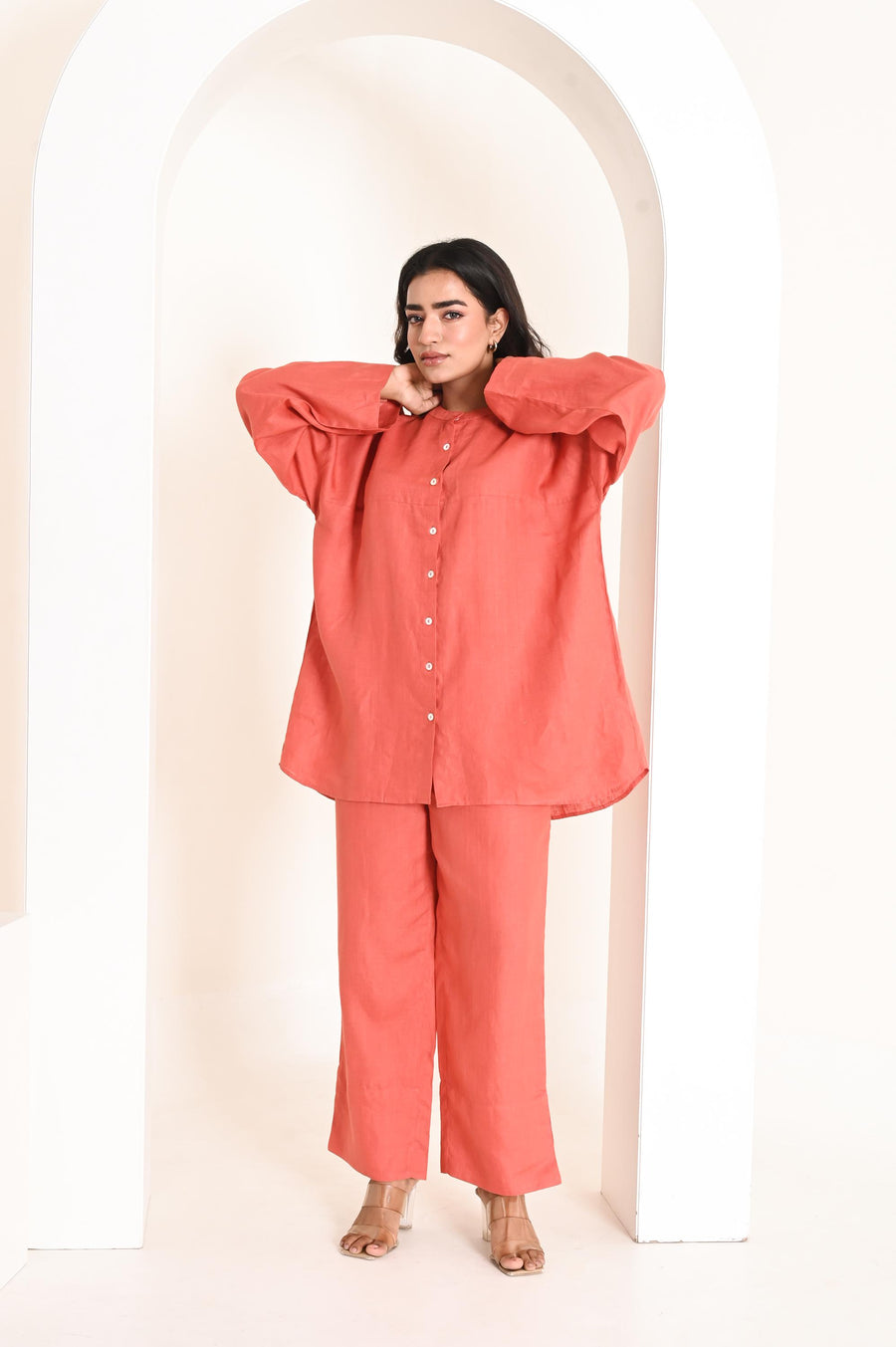 Linen Co-ord Set, Oversized Shirt & Trousers: woman in coral shirt with arms extended, showing loose sleeves and trousers