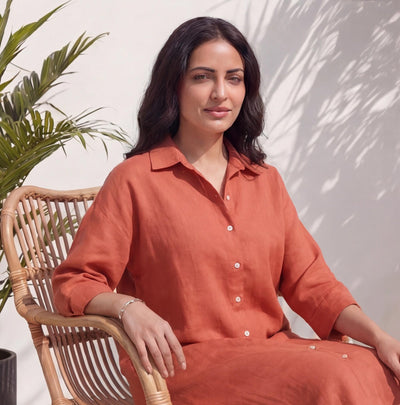 Linen Tunic Dress, 3/4 Sleeve: woman seated on a rattan chair in Terracotta shirt dress