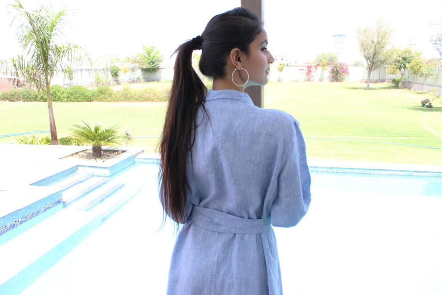 Long Sleeve Linen Wrap Dress: woman in light blue linen wrap dress seen from behind, turning to the pool
