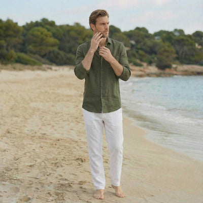 Men's European Linen Shirt, Beach: man in Moss Green linen shirt, hand at chin, standing by the shore