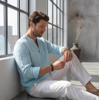 Men's Linen V-Slit Neck Shirt: man seated on the floor adjusting his sleeve, light blue linen shirt
