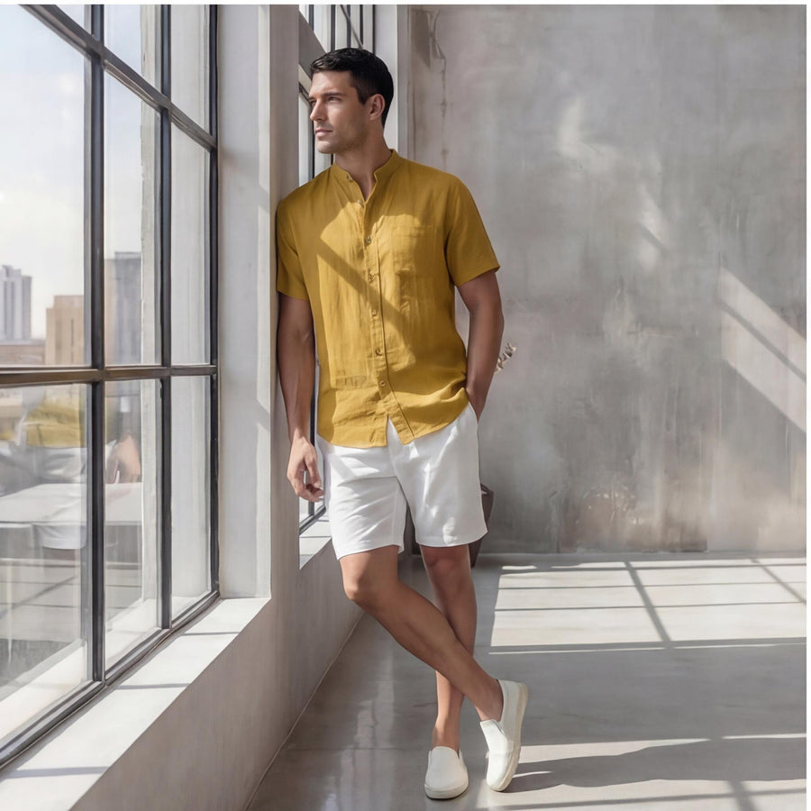 Men's Oversized Short Sleeve Linen Shirt: man leaning by a large window in mustard shirt and white shorts