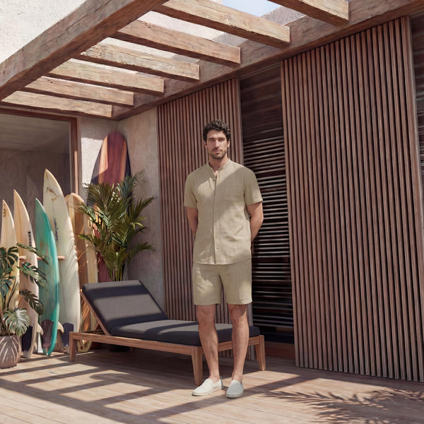 Men's Short Sleeve Linen Shirt, Resort Fit: man in Beige linen shirt and shorts standing by a lounger and surfboards
