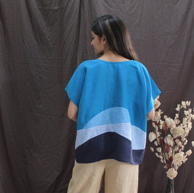 Sky Blue Abstract Linen Top: back view of blue linen top with moon print and beige trousers