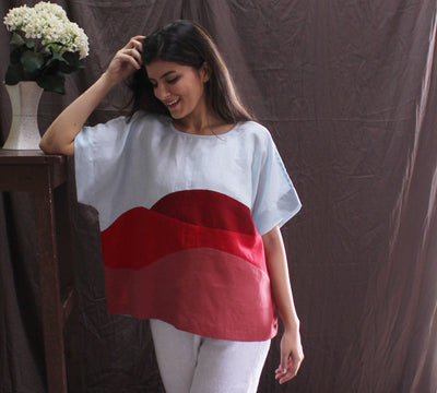 Sky Blue and Red Linen Top, Boxy Fit: woman in Sky Blue and red colourblock boxy top with white trousers, hand at hair