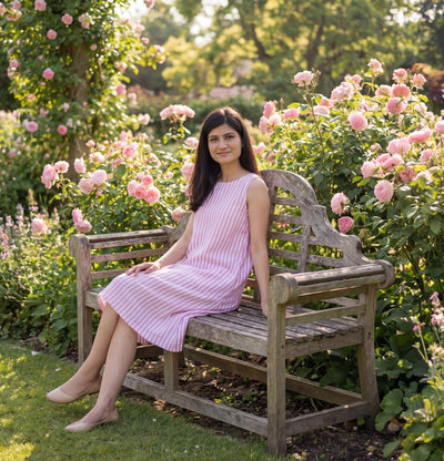 Sleeveless Linen Midi Dress with Pockets: woman in pink striped sleeveless linen dress smiling on a wooden bench