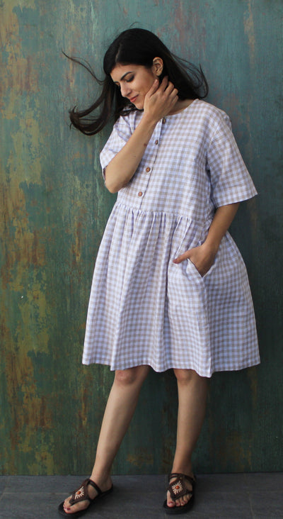 Smocked Linen Midi Dress, Short Sleeve: woman in gingham linen dress with smocked waist, hand in pocket, teal wall